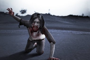 Sahada kan ve yara içinde sürünen korkunç bir zombi.