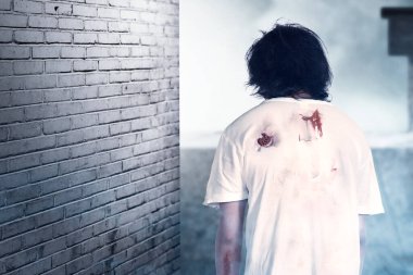 Korkunç bir zombi. Vücudunda kan ve yara var. Terk edilmiş binada duruyor.
