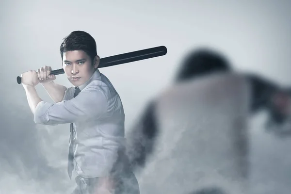 Asian man standing with a baseball bat in his hand ready to attack zombies with a smog background