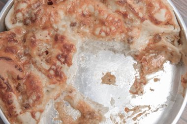 Tahta masadaki tepside bir dilim pizza.