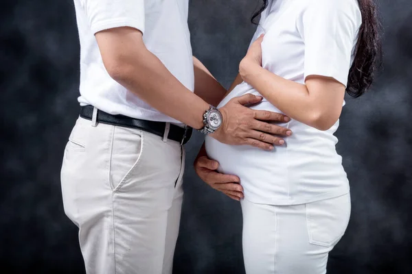 妊娠カップルタッチ腹とともに手黒背景 — ストック写真