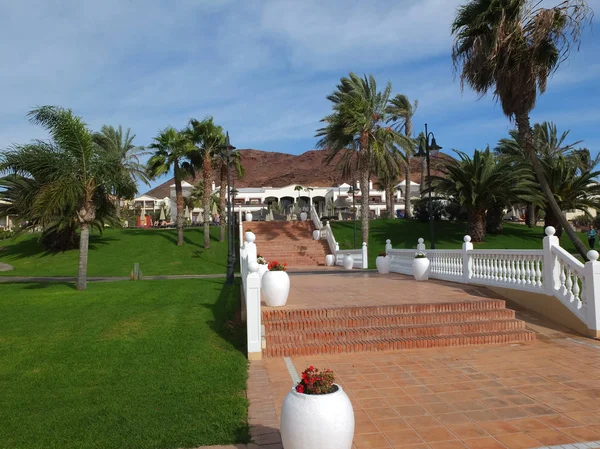 Lanzarote, İspanya - Aralık 09,2013: Lanzarote palmiye ağaçları, kırmızı Teracotta merdiven otel ve arkasında volkanik dağlardan LUCIOUS yeşil çimenler Aralık ayında.