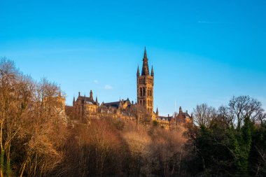 Geç öğleden sonra güneş Glasgow Üniversitesi görkemli kuleleri için ağaçların arasından arıyorsunuz.