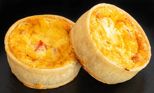 Küçük Bir Siyah Kayrak Tepsi üzerinde İki Küçük Taze Bakes Quiches.