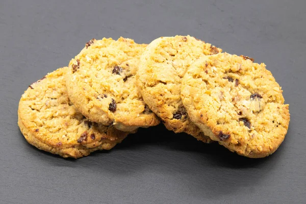 Meyve ve yulaflı kurabiyeler siyah tahtada, fırından yeni çıkmış ve yemeye hazır..