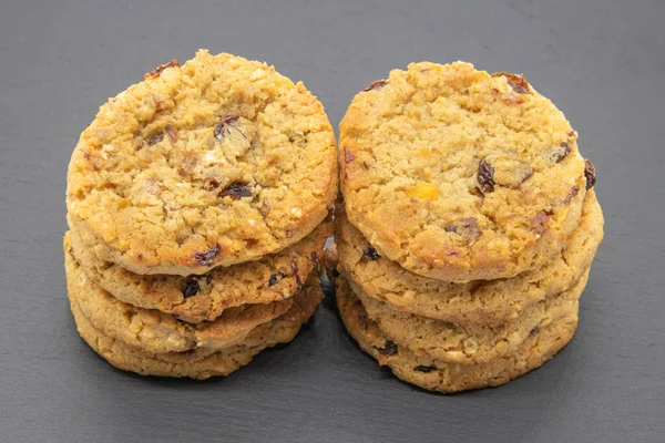 Meyve ve yulaflı kurabiyeler siyah tahtada, fırından yeni çıkmış ve yemeye hazır..