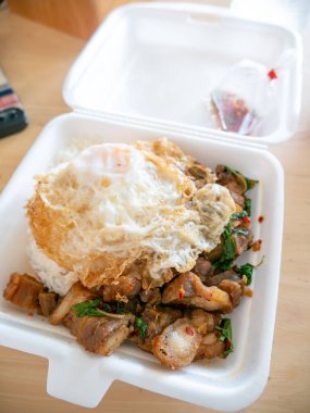 Kızarmış yumurtalı kızarmış domuz fesleğeni ve köpük kutusu..