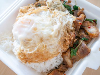 Kızarmış yumurtalı kızarmış domuz fesleğeni ve köpük kutusu..