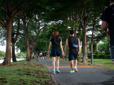 Lush Green Parkı 'nda Gölge Ağaçlarıyla Koşan ve Yürüyen İnsanlar Egzersizi - Açık Hava Spor Etkinliği.