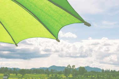 Ev terrece gökyüzüne yağmur bulutu altında yeşil şemsiye.