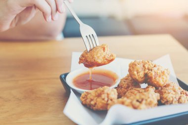 Bir çatal için kullanan kadın elini al biber sos için daldırma bir kızarmış tavuk.