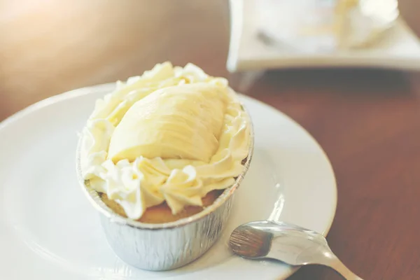 A piece of Durian cake put on the white dish with a silver spoon for serving to sweet lover people.