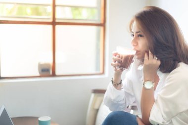 Kadın çok rahatlatıcı kafede sıcak çikolata içme ile beyaz gömlekli.