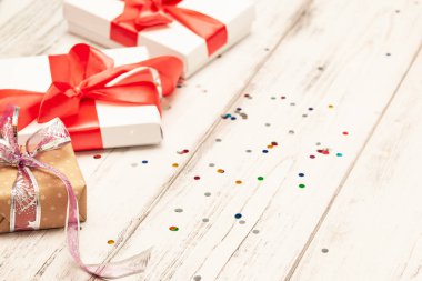 Arka plan metin için yer ile yönetim kurulu bir kahverengi hediye kutusu ve iki beyaz kağıt kutusu beyaz tahta üzerine kırmızı kurdele ile.