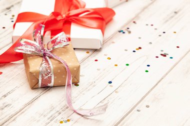 Arka plan metin için yer ile yönetim kurulu bir kahverengi hediye kutusu ve iki beyaz kağıt kutusu beyaz tahta üzerine kırmızı kurdele ile.