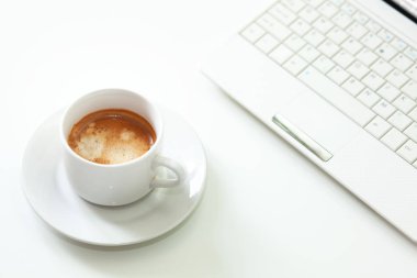 Beyaz masada kahve bardağı ve laptop. Seçici odak.