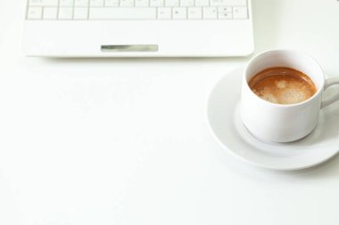 Kahve bardağı, laptop ve beyaz masada. Seçici odak.