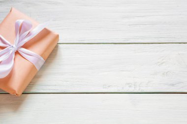 Beyaz ahşap arka plan üzerinde şeftali renkli hediye kutusu. Doğal ışık