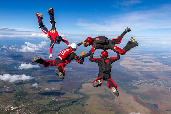 跳伞照片四个运动跳伞运动员在自由落体中建立了一个形象 极端体育概念 图库照片