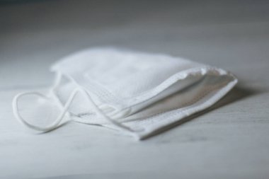 Tek kullanımlık koruyucu maske masanın üzerinde yarı yarıya katlanmış, seçici bir şekilde duruyor.