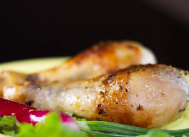 Sebzeli bir tabakta kızarmış tavuk bacağı.