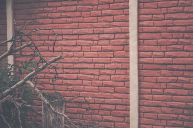 Kırmızı tuğla duvar ve birkaç ağaç dalı olan bir arka plan