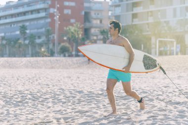 Plaj su sporları adam güneş ışığı ile yaz tatil tatil sırasında mutlu çalışan vücut surfboard ile sörf.