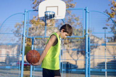 Kolsuz bir sarı giyen sahada ayakta genç basketbolcu