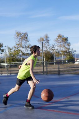 Bir açık havada sahada basketbol oynarken Teenage