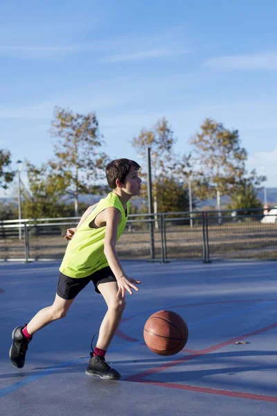 Bir açık havada sahada basketbol oynarken Teenage