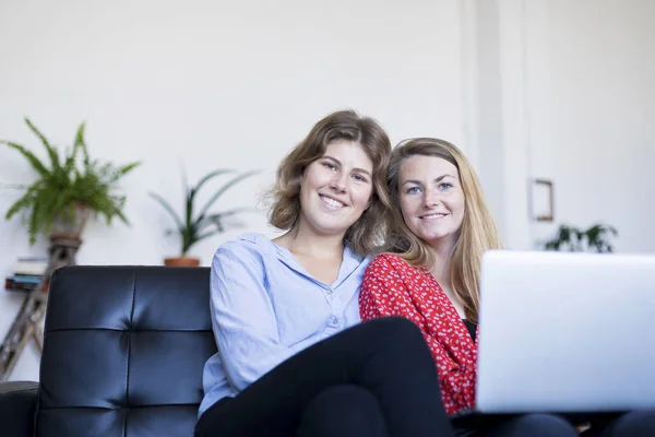 Dos Jóvenes Sonrientes Sentadas Sofá Con Portátil — Foto de Stock