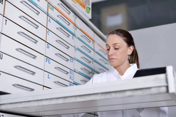 Young pharmacist woman looking for medicine in the store desk