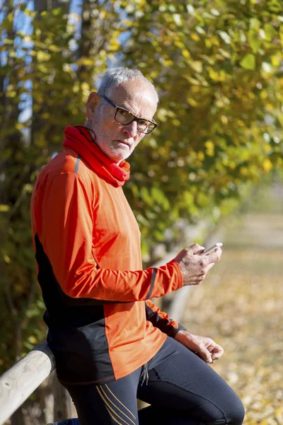 Senior runner in nature with smartphone.