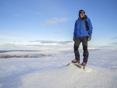 Yalnız dağcı dinlen bulutların üzerinde yüksek karlı dağda güneşe