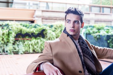 Sokağın ortasında kış giysileri giyen genç adam. Ceket, kot ve beyaz tatlı ile modern saç modeli ile genç adam.