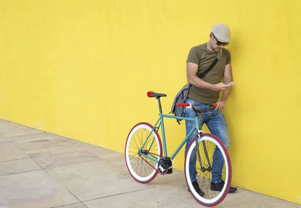 Homem Usando Telefone Inteligente Enquanto Está Bicicleta Contra Parede Amarela — Fotografia de Stock