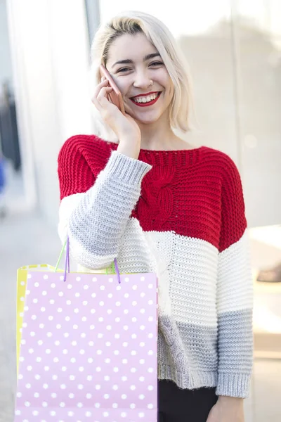 一个微笑的年轻女子在使用手机时站在购物中心的前面 — 图库照片
