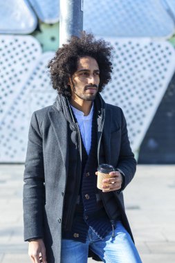 Hoş gülümseyen, şehir sokakta duran paket servisi olan restoran kahve ile hipster afro adam ayakta. Bin yıllık üretimi