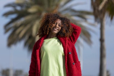 Yolu görünümlü kamera güneşli bir günde gülümseyen üzerinde duran genç güzel kıvırcık kadın önden görünümü