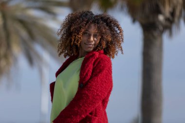 Yolu görünümlü kamera güneşli bir günde gülümseyen üzerinde duran genç güzel kıvırcık kadın önden görünümü