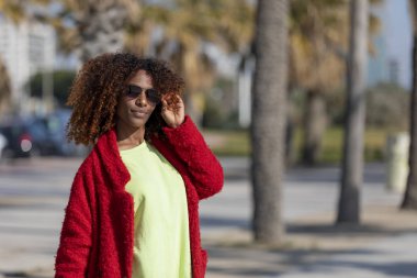Yolu görünümlü kamera güneşli bir günde gülümseyen üzerinde duran genç güzel kıvırcık kadın önden görünümü