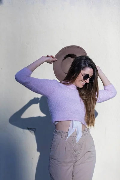 Widok z przodu piękna młoda kobieta modny sobie okulary przeciwsłoneczne i kapelusz stojących na ulicy podczas pozowanie na kamery w słoneczny dzień — Zdjęcie stockowe