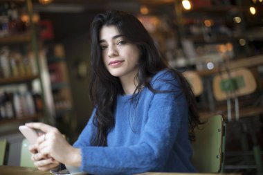 Genç güzel kadın kahve içme ve onun Smartphone kentsel kafede kapalı oturan kullanın. Cafe şehir yaşam tarzı. Güzel kız Casual portre