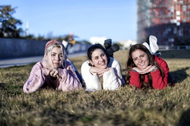 sonbaharda bir parkta çim üzerinde yatan üç kız