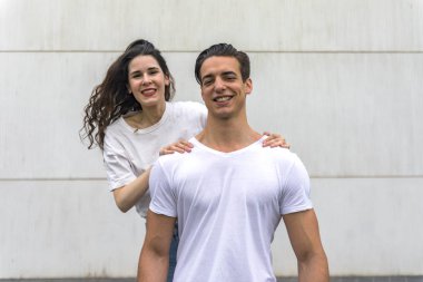Güzel genç çift sarılma ön görünümü, kamera bakıyor ve açık havada ayakta iken gülümsüyor