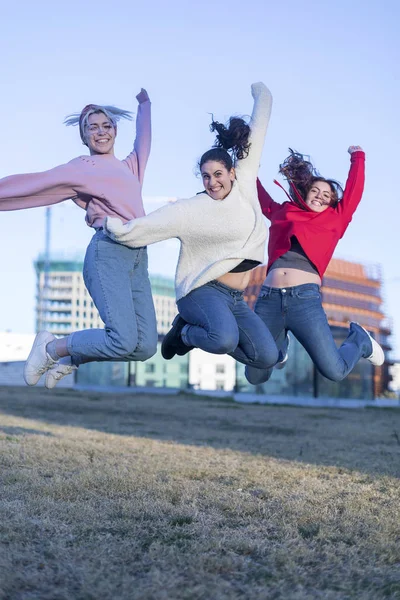 Tři šťastné dívky, přátelé skáčou vysoko na modré obloze v létě venku — Stock fotografie