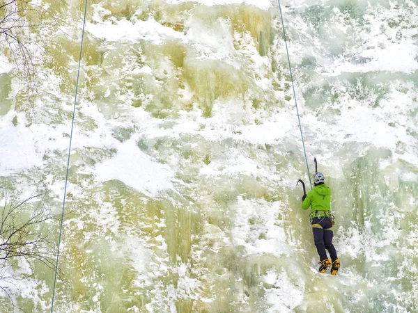 Um homem usando jaqueta azul escalando parede de gelo — Fotografia de Stock