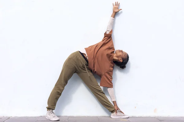 Stylische attraktive junge Läuferin in schwarzer Sportbekleidung beim Aufwärmen im Freien, bevor sie gegen die Wand läuft — Stockfoto