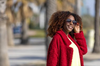 Güneşli bir gün kamera bakarak yolda gülümseyen genç güzel kıvırcık kadın ön görünümü
