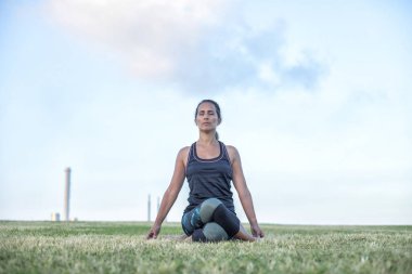 Parkta yoga egzersizi yapan güzel bir kadın.